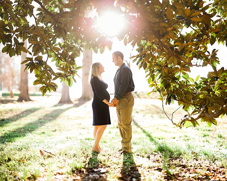Husband and wife stand in the clearing of a magnolia tree at Independence Park in Charlotte NC