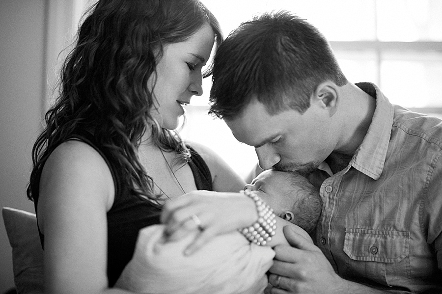 Mother holds newborn baby as father kisses her forehead in Charlotte NC