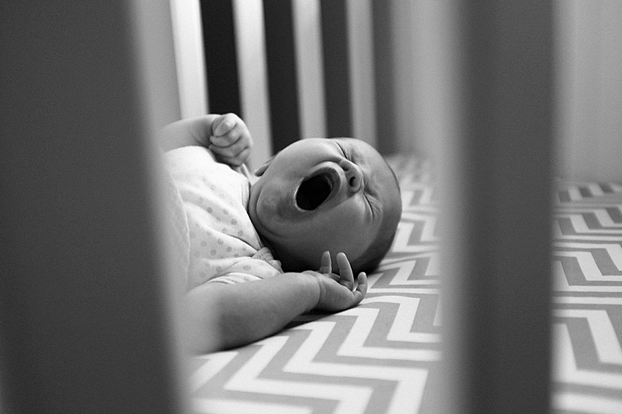 Baby yawns in crib with chevron sheets in Charlotte NC