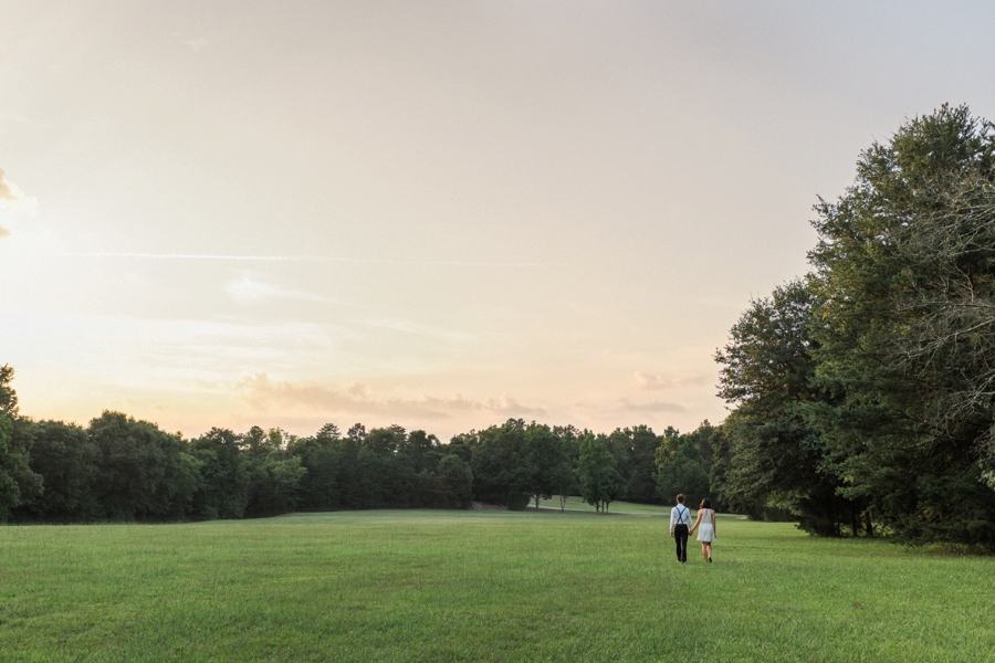 Couple walking hand in hand in field in Charlotte NC