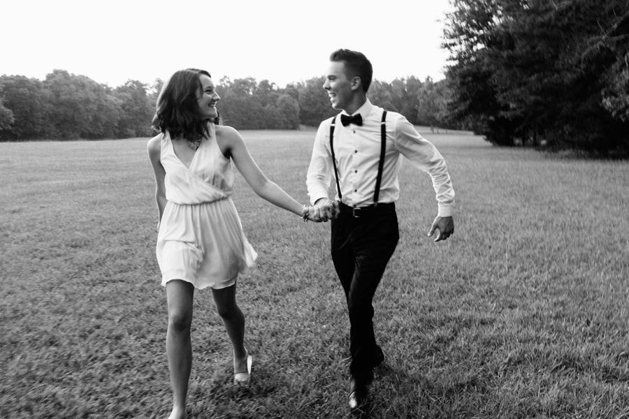 Couple running hand in hand in field in Charlotte NC