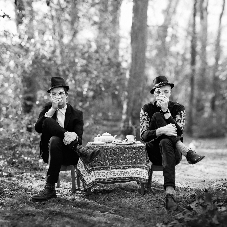 Two grown men in small chairs sipping tea for The Cookie Cult in Charlotte NC