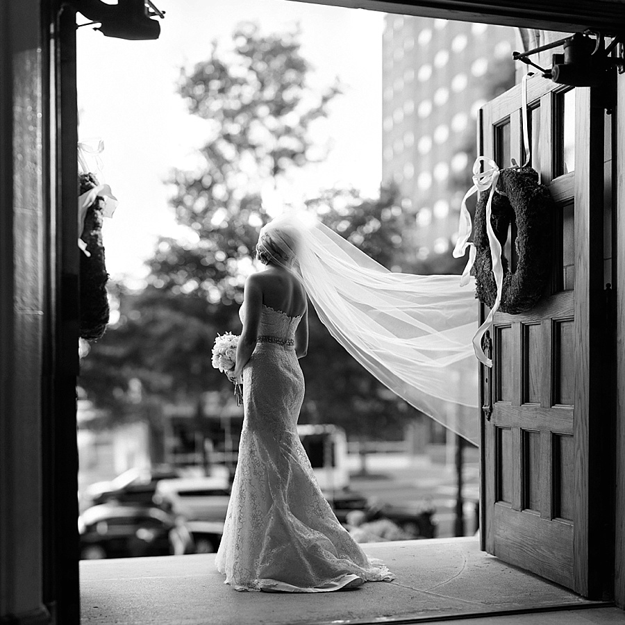 Bride with sweeping veil standing in the doorway of the First United Methodist Church in Charlotte NC