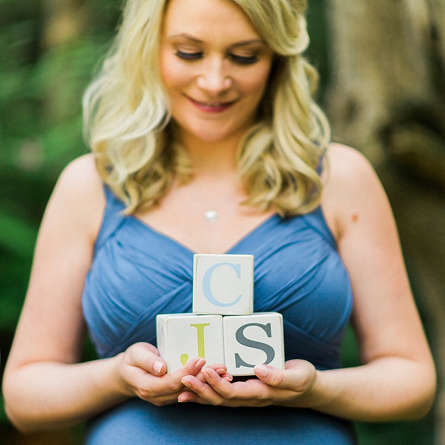 Pregnant mother holds blocks of baby's initials at Wing Haven Gardens in Charlotte NC