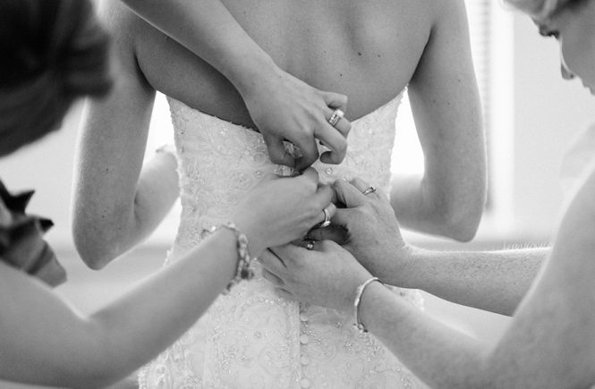 Bridesmaid zipping bride into dress at the Myers Park United Methodist Church in Charlotte NC