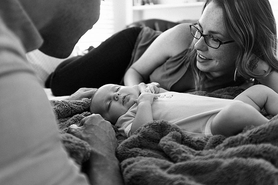Mother and Father look on as their baby sleeps on bed in Charlotte NC