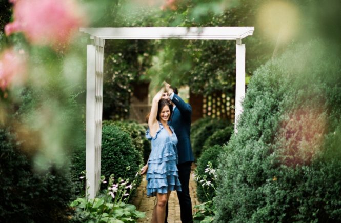Couple hugging under arbor at Wing Haven Gardens in Charlotte NC